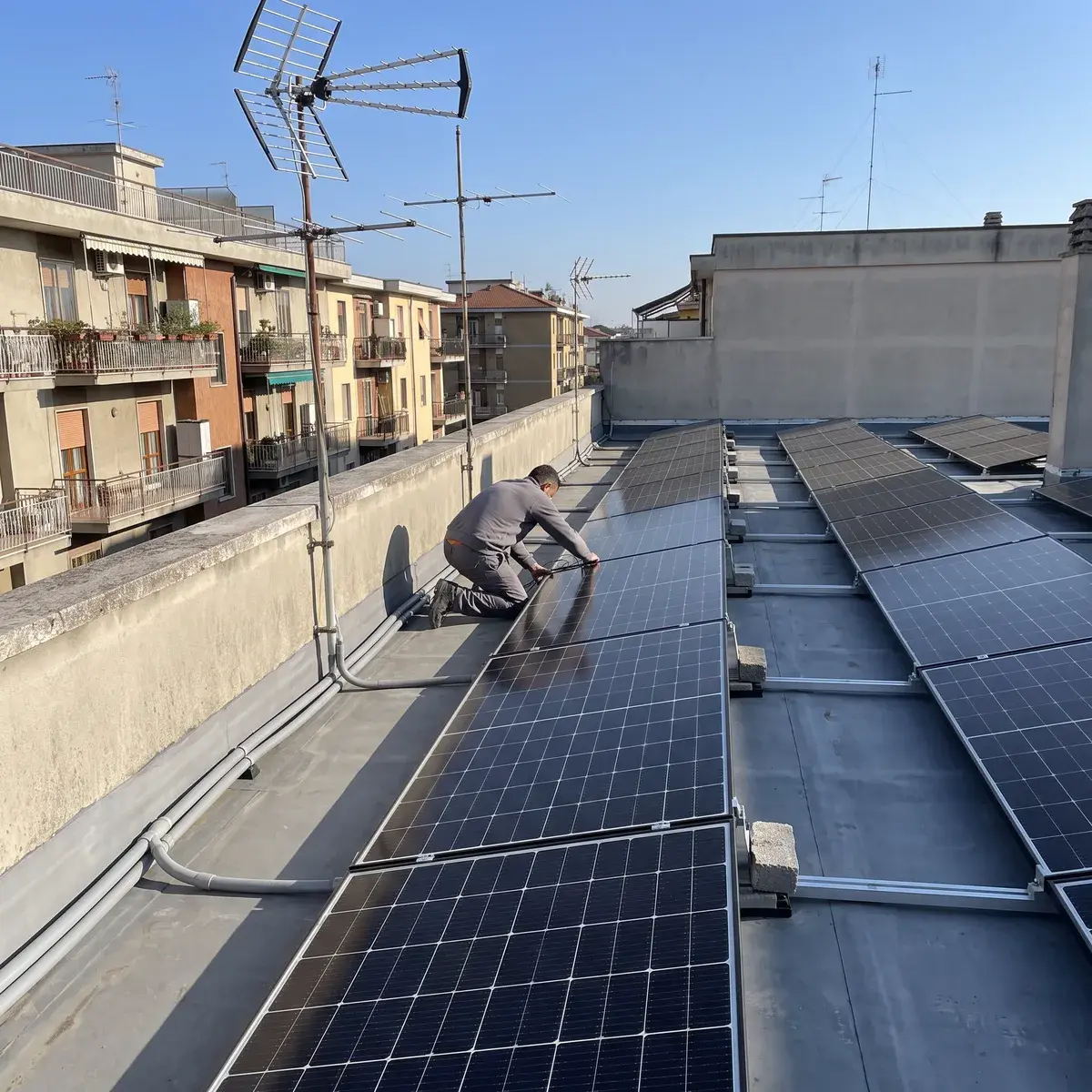 Tecnico tra le file di moduli LONGi Hi-MO X10 Explorer su telai zavorrati, sul lastrico solare di un condominio.