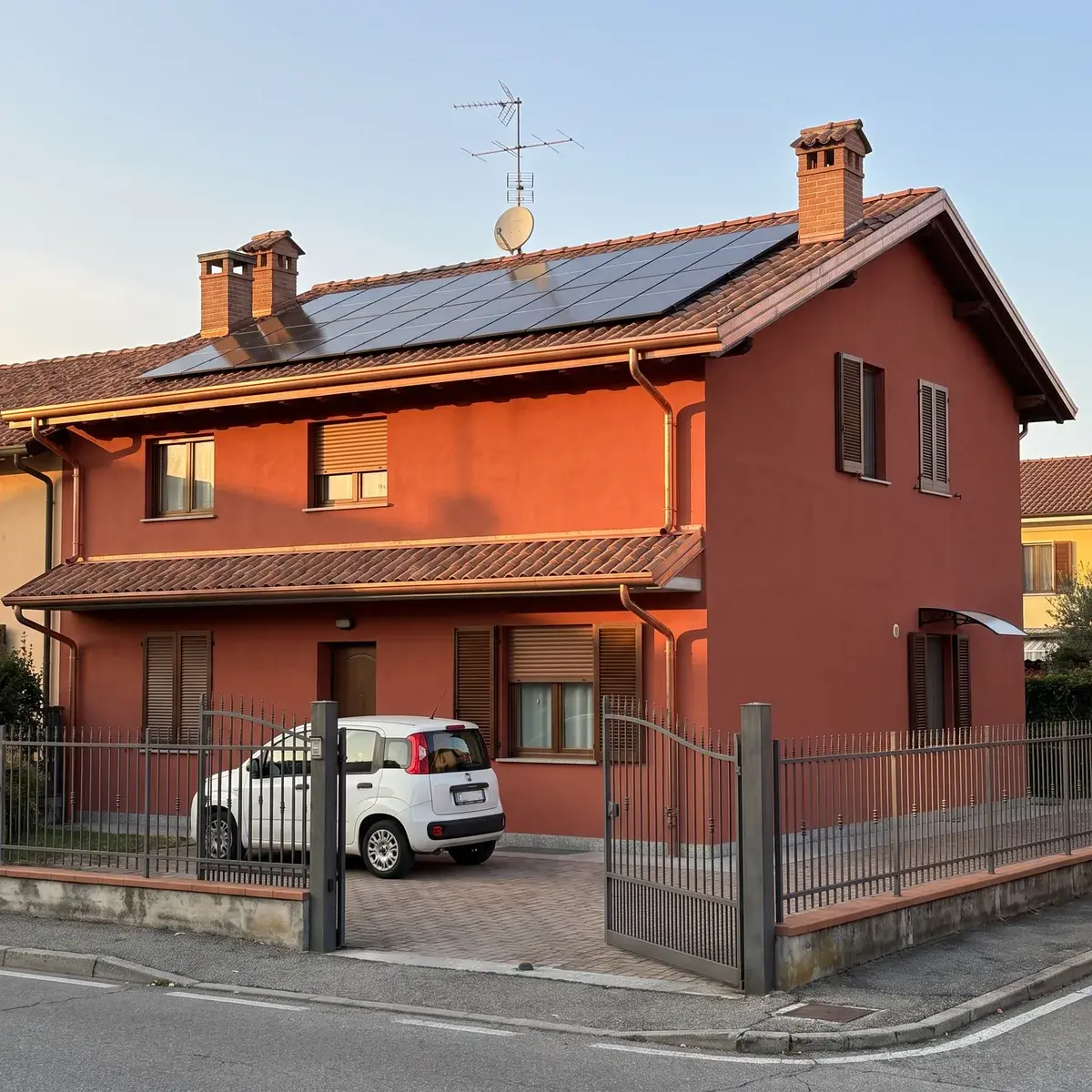 Villetta bifamiliare in intonaco rosso con un impianto da circa 6 kW di moduli LONGi Hi-MO X10 Artist full black sul tetto in coppi.