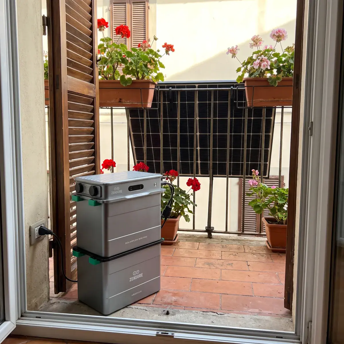 Zendure SolarFlow 800 Pro con batteria AB2000X sul pavimento in cotto di un balcone, con i moduli fissati alla ringhiera tra i gerani.