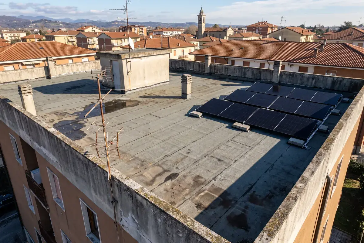 Lastrico solare di un condominio con un piccolo campo di moduli Trina Vertex S+ su zavorre in un angolo e il resto del tetto libero.