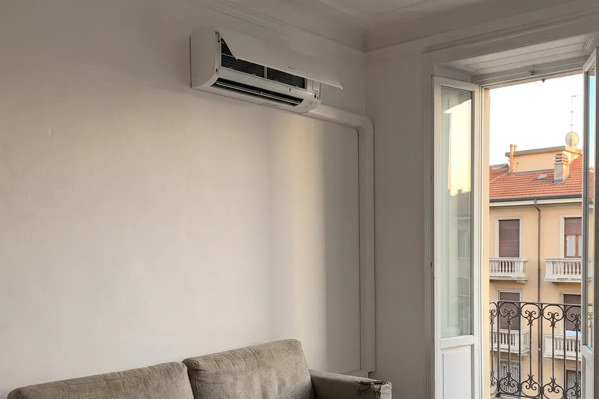 Unità interna di un climatizzatore Daikin Perfera aria/aria in un soggiorno con porta-finestra sul balcone.