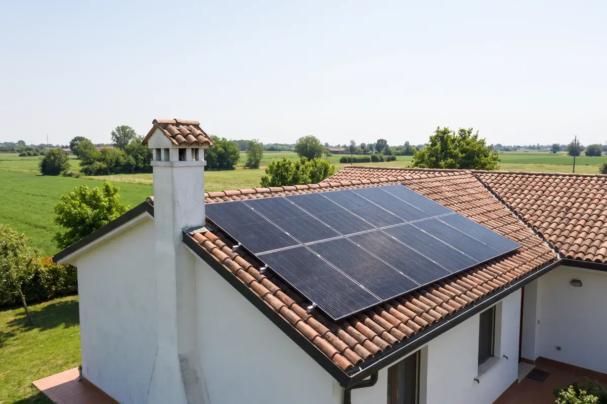 Villetta con muri intonacati e tetto in coppi nella pianura veneta, con due file di moduli fotovoltaici AIKO NEOSTAR full black sotto il sole di mezzogiorno.