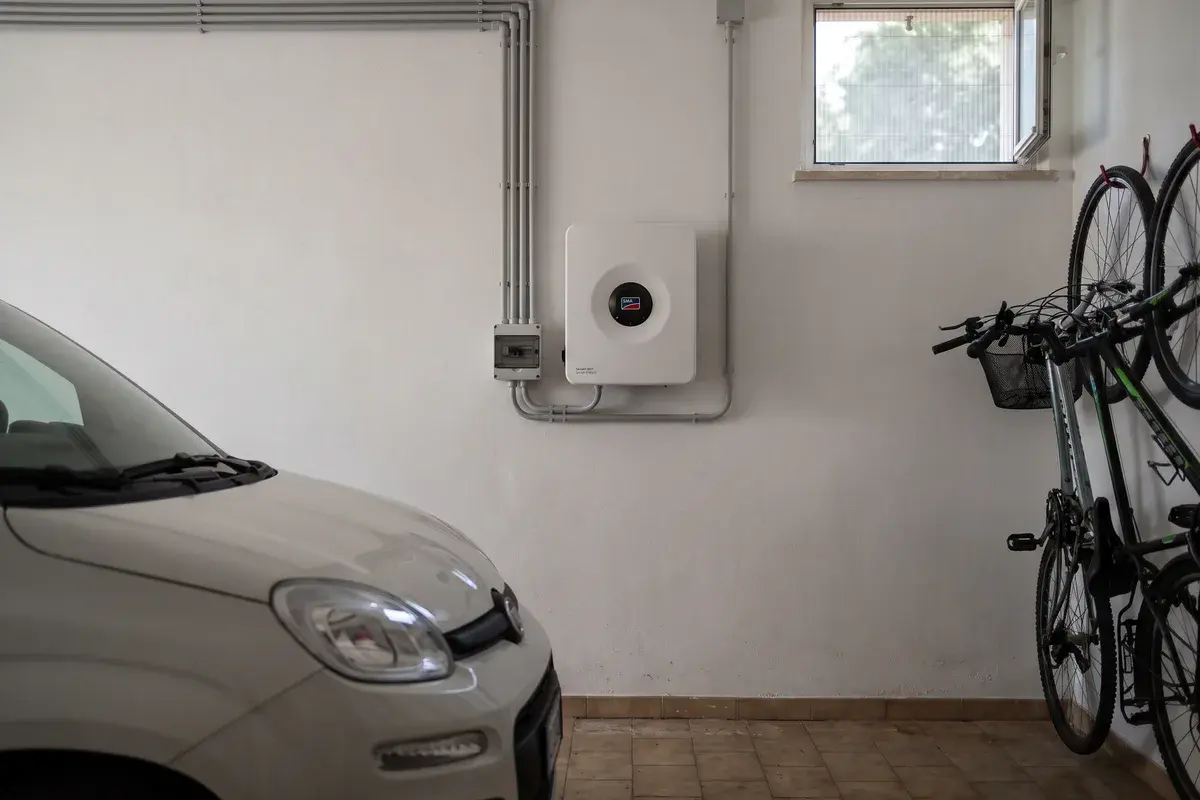 Inverter SMA Sunny Boy Smart Energy montato in un garage ombreggiato e ventilato, con spazio libero intorno e canaline in PVC grigio.